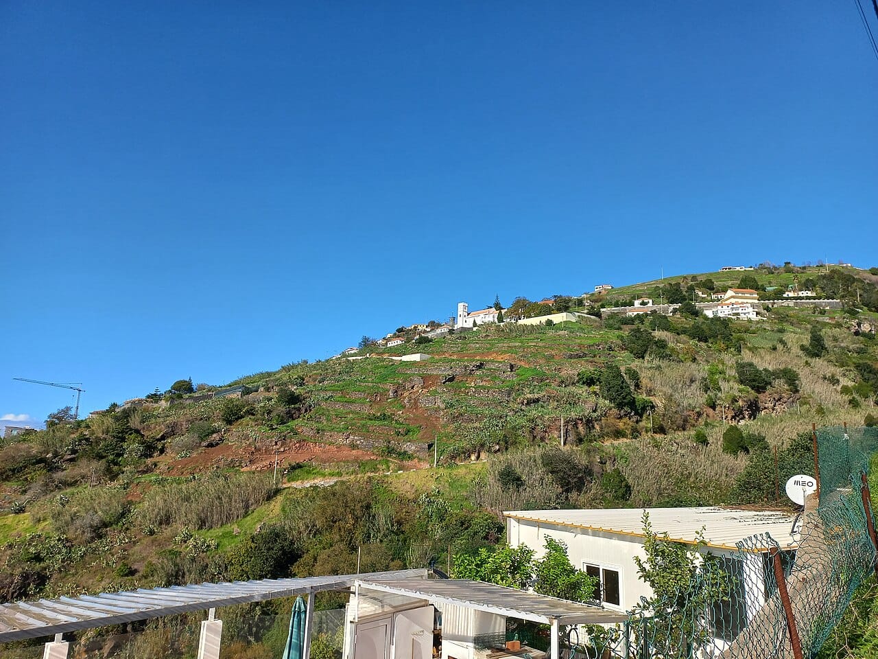 Houses and cultivated slopes at Fajã da Ovelha, showing the hillside terrain of a village visit.