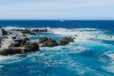 Ondas do Atlântico rebentam em redor das piscinas vulcânicas do Porto Moniz, junto ao passeio marítimo.
