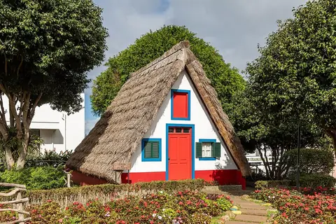 Ein weiß-rot-blaues strohgedecktes Haus in Santana steht neben den Gartenwegen des Ortsrundgangs.