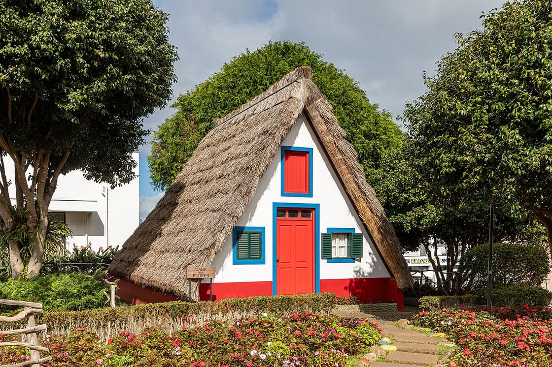 Ein weiß-rot-blaues strohgedecktes Haus in Santana steht neben den Gartenwegen des Ortsrundgangs.